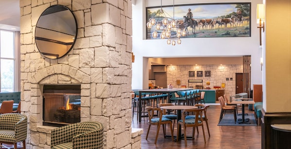 Ein gemütliches Restaurant mit Kamin aus Stein, Holztischen und Zickzack-Stühlen.