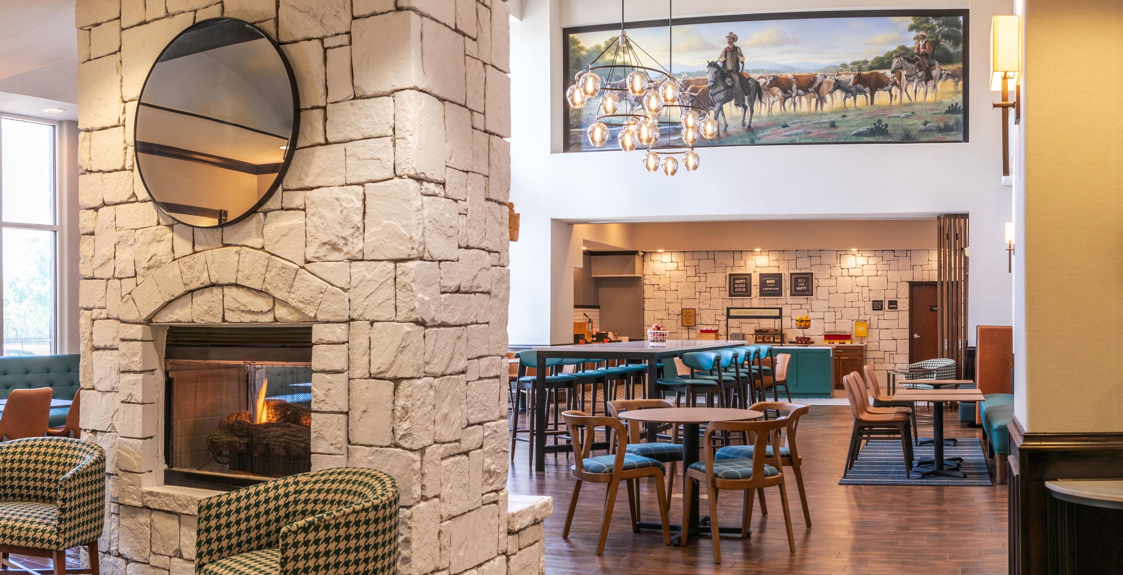 A spacious lobby with a stone fireplace, a bar area, and seating arrangements.