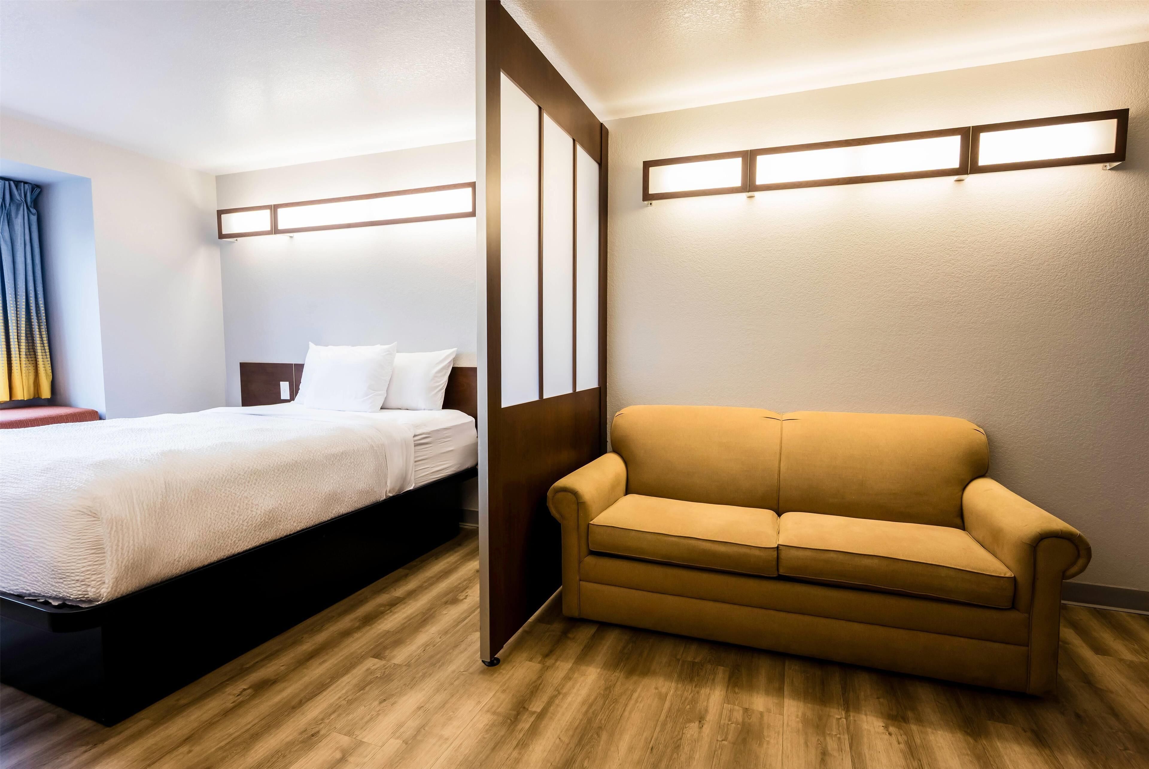Ein Hotelzimmer mit einem Bett, einer Couch und Holzboden.