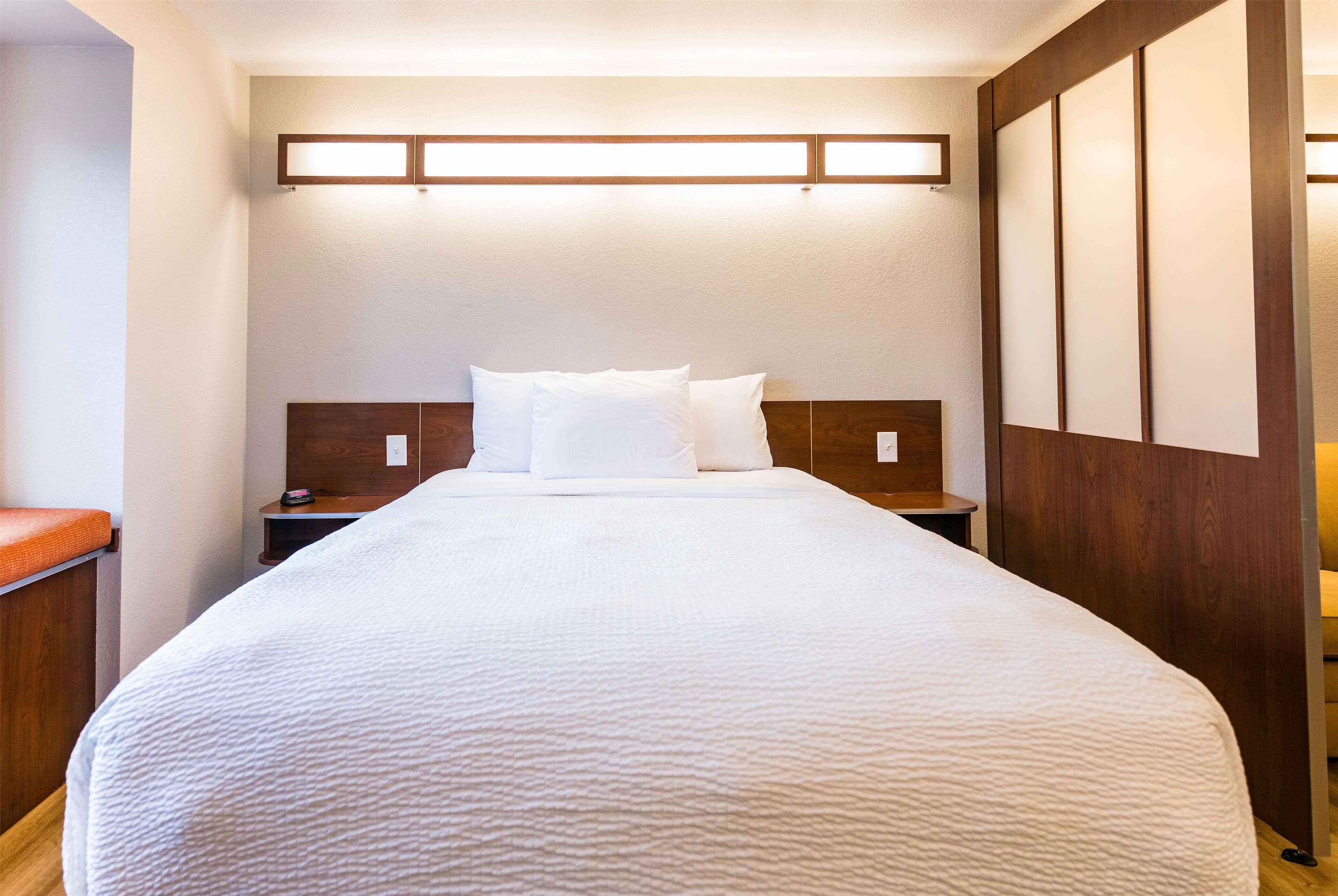 A neatly made bed with white linens in a hotel room.