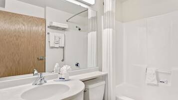 Une salle de bain moderne équipée d’un lavabo, d’un miroir, d’une douche et de toilettes.