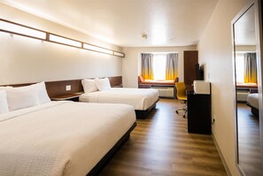 A hotel room with two beds, a desk, a chair, and a TV. - Microtel Inn & Suites by Wyndham Cheyenne (Cheyenne)