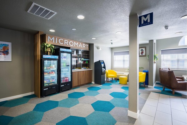 A modern interior with a Micromart kiosk, vending machines, and a seating area with yellow chairs.