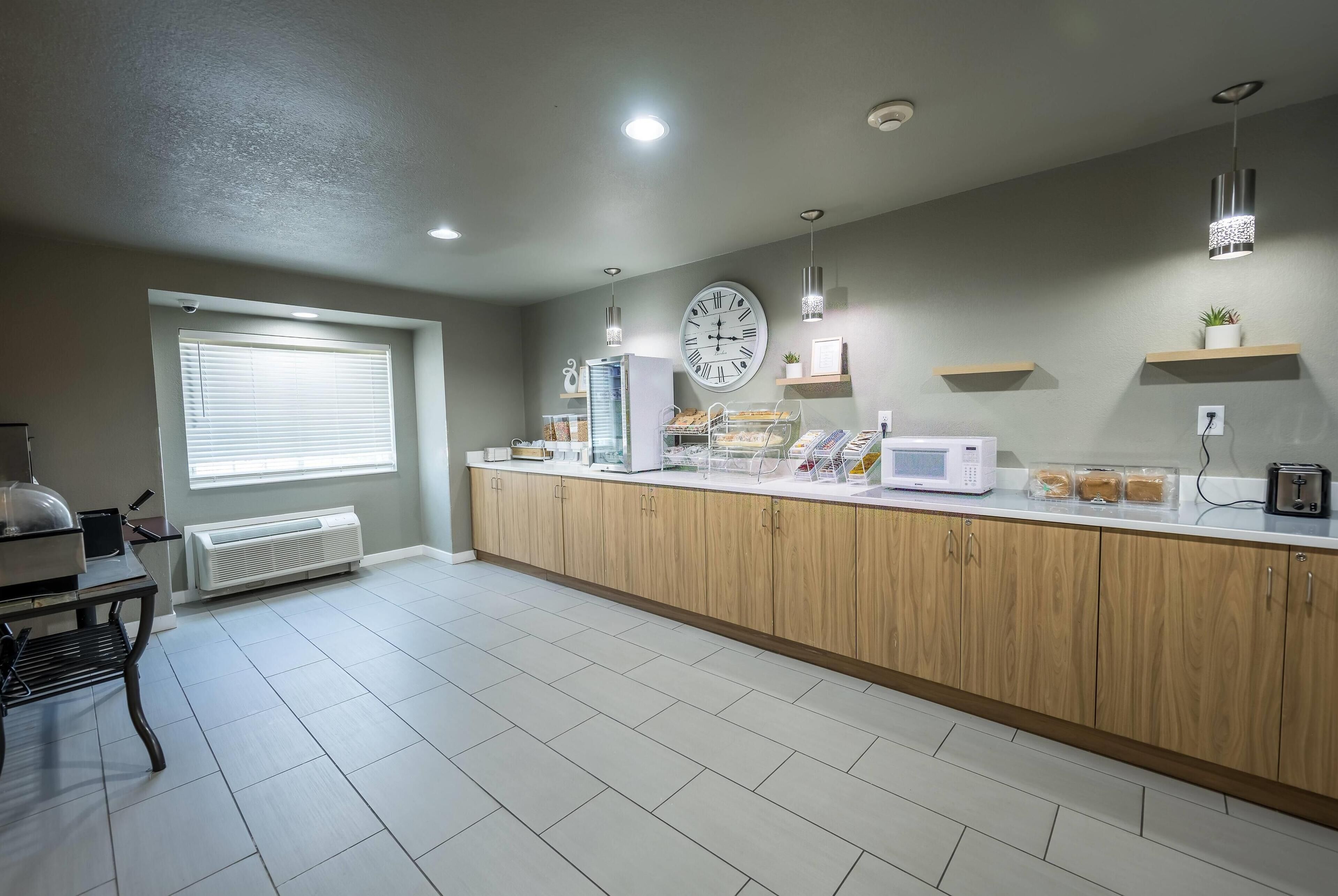 Une cuisine moderne avec des meubles en bois, un plan de travail blanc et une horloge au mur.