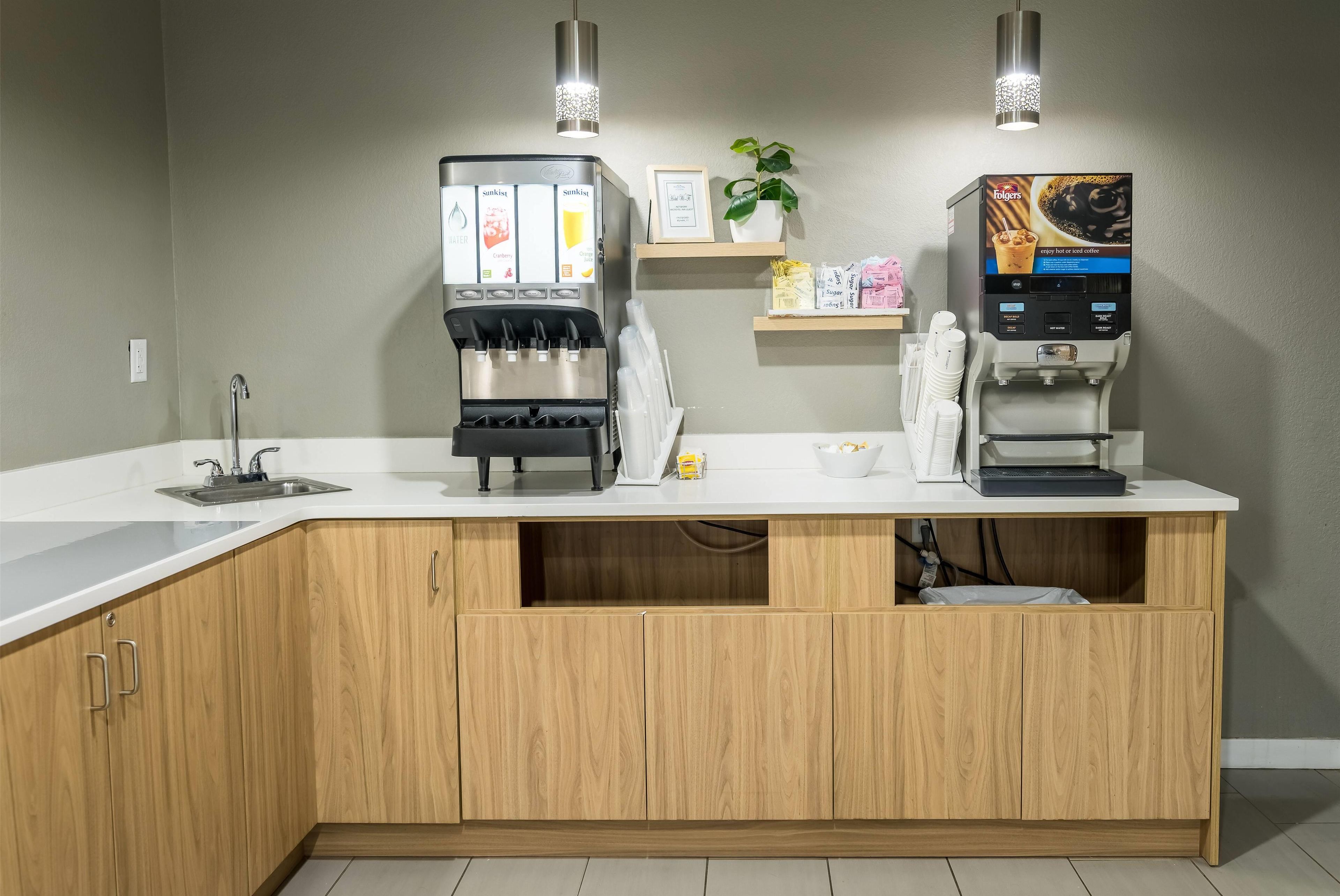 Una cocina con cafetera, pileta y muebles de madera.