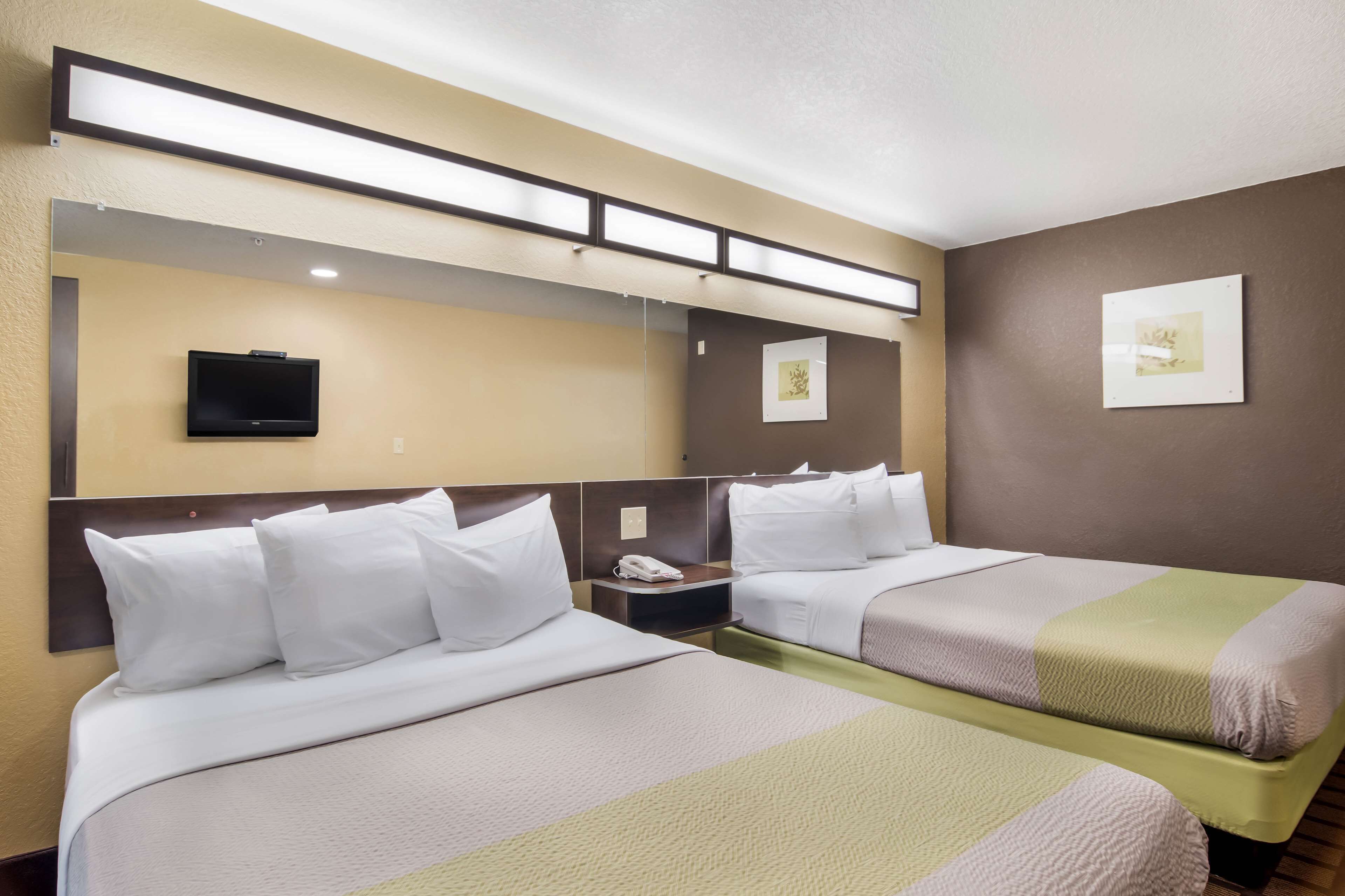 Een hotelkamer met twee bedden, een aan de muur bevestigde televisie en kunstwerken aan de wanden.