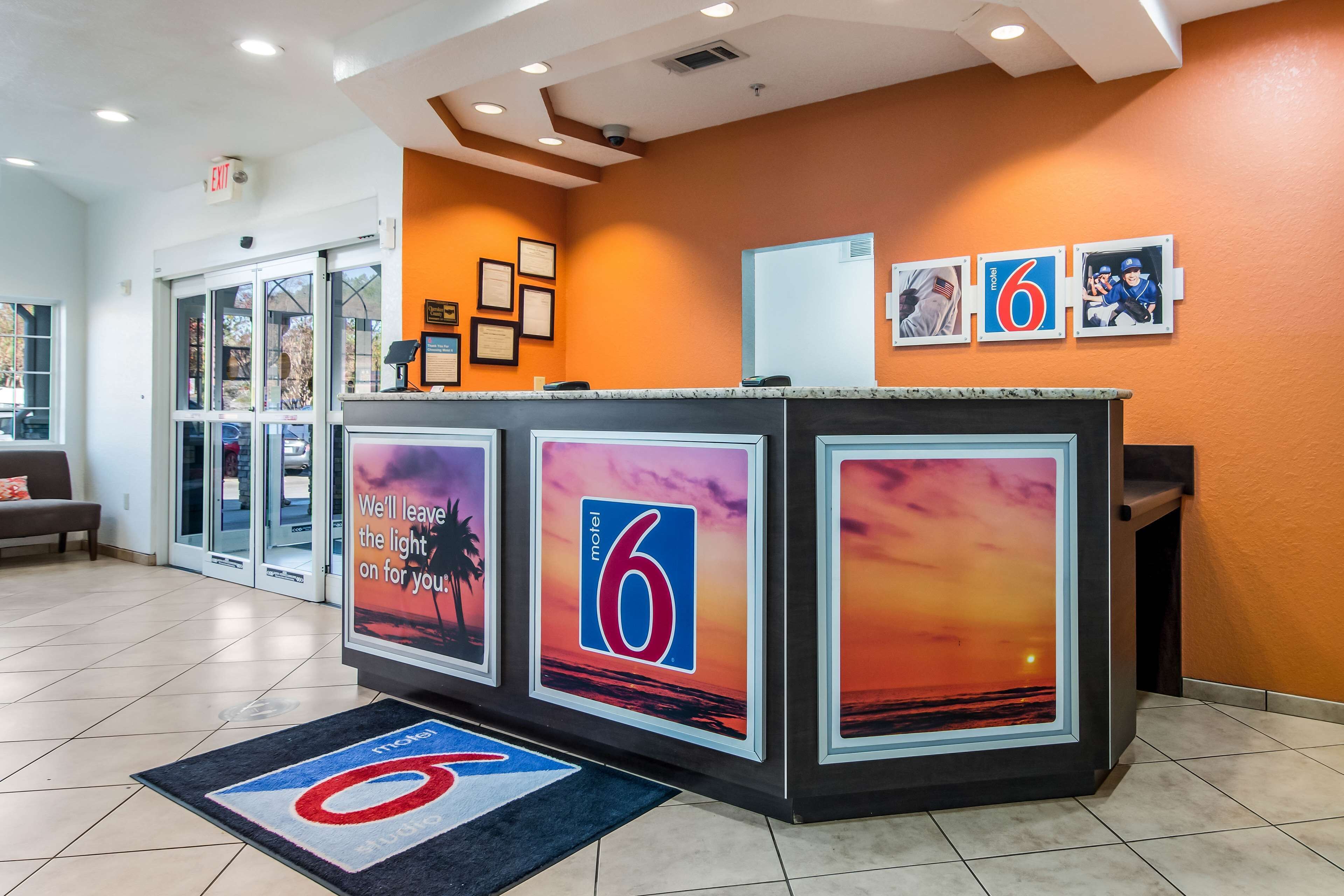 A hotel reception area with a modern design, featuring a reception desk, framed certificates, and a large number '6' sign.
