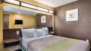 A hotel room with a bed, bedside table, and a large mirror.