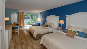 A hotel room with two beds, a desk, and a window with a view.