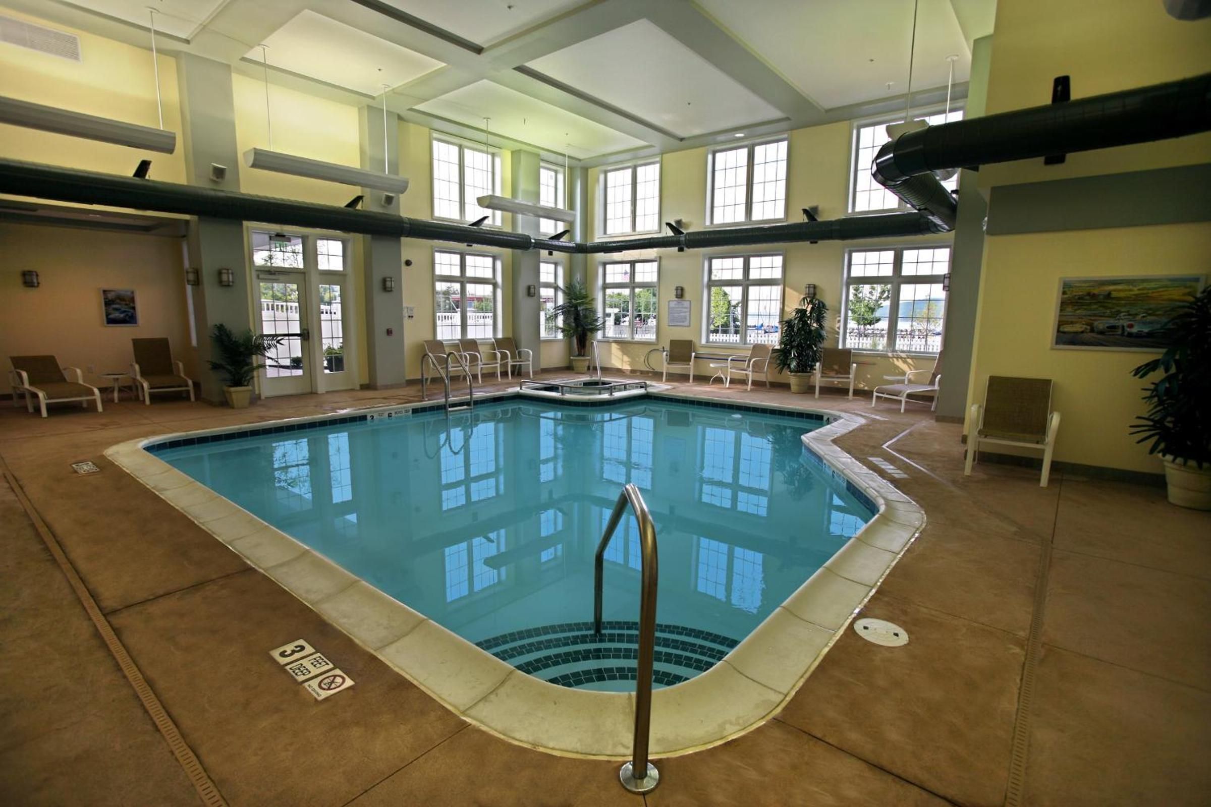 An indoor swimming pool with clear water, surrounded by lounge chairs and potted plants.