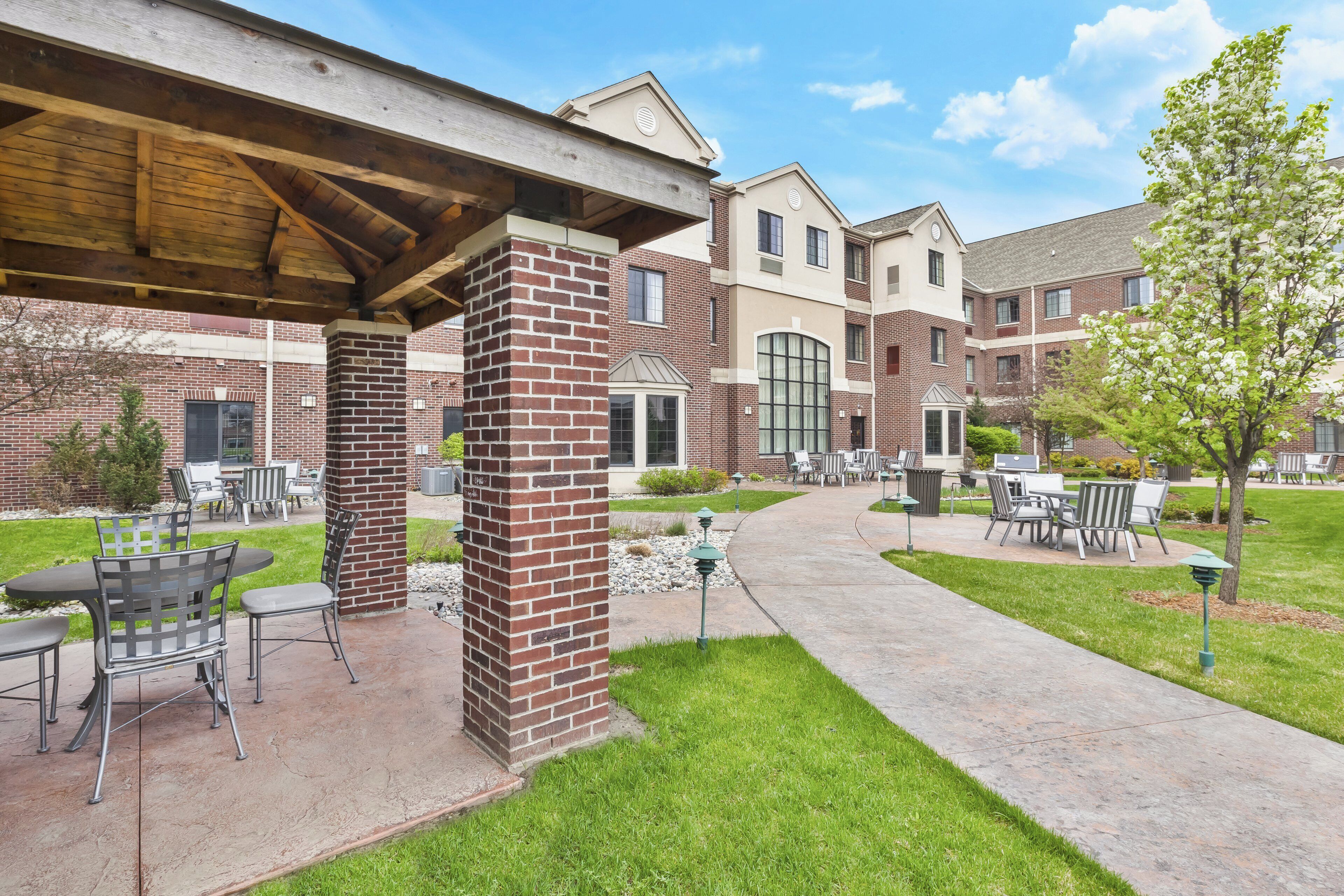 A courtyard with outdoor seating, a brick column, and a covered area.