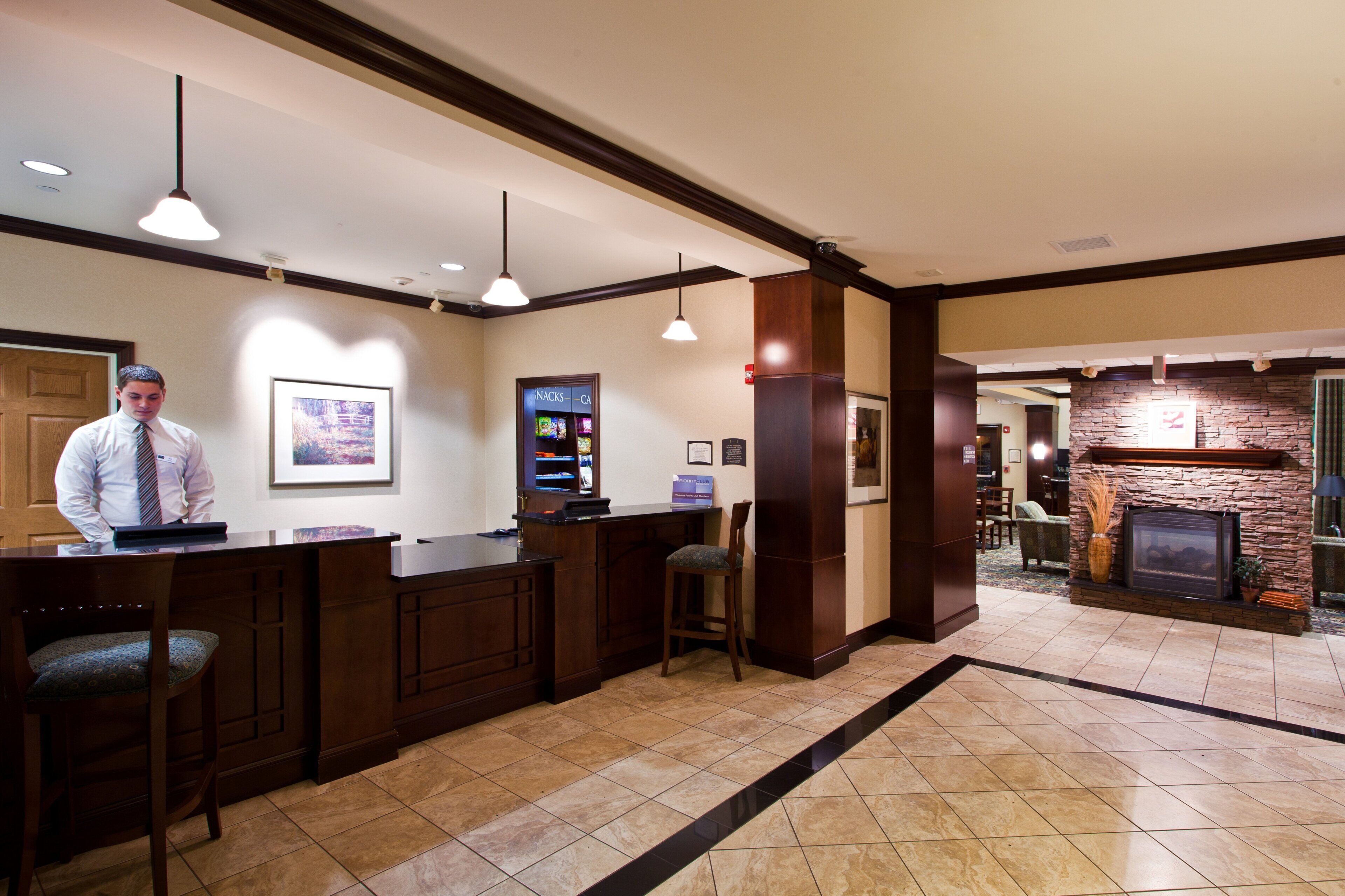A hotel lobby with a reception desk, a fireplace, and a framed picture on the wall.