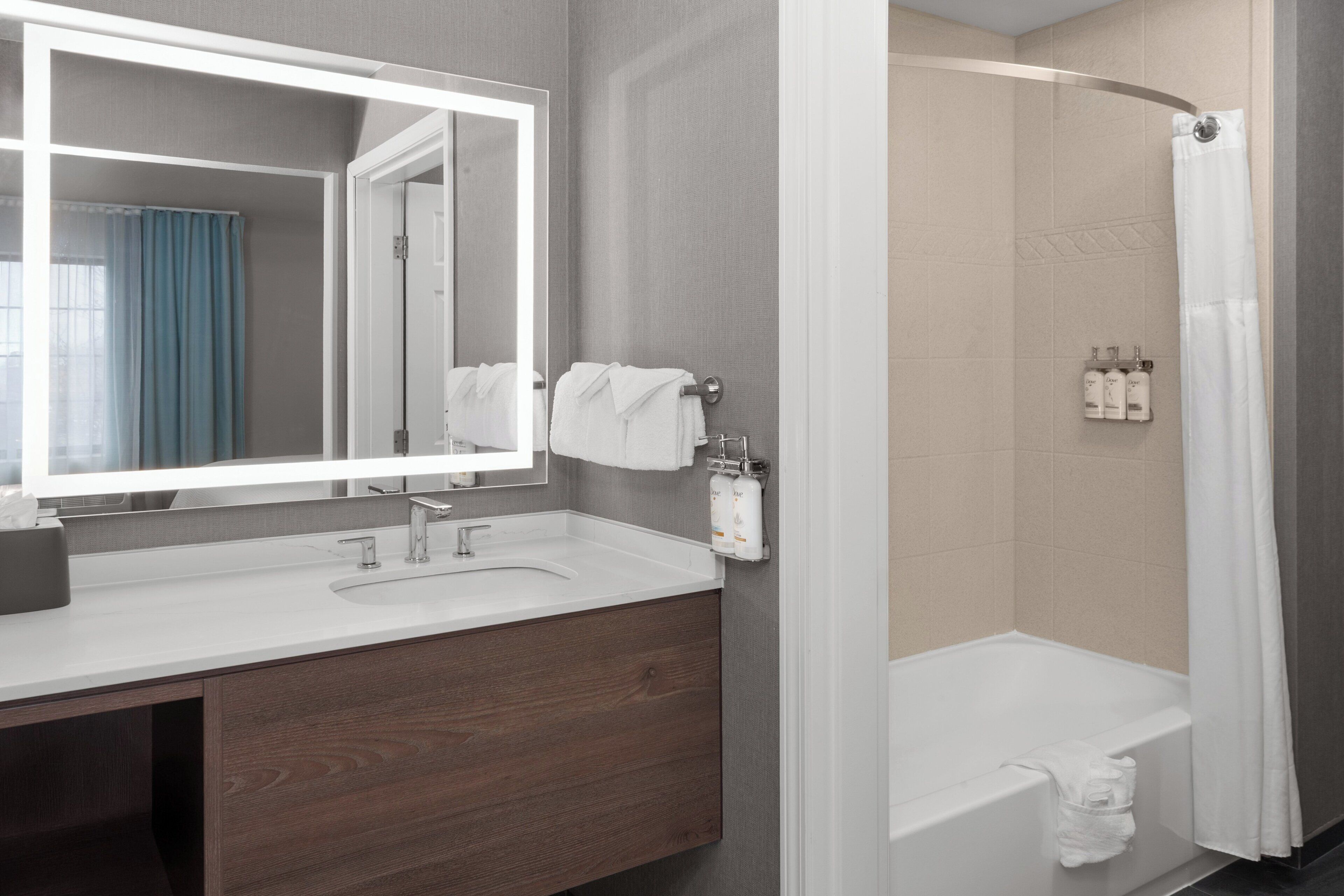 Een moderne badkamer met een grote spiegel, een wastafel, een douche en een bad.
