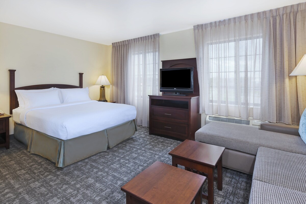 Habitación de hotel con una cama grande, un televisor de pantalla plana, un sofá, una mesita de centro y un escritorio.