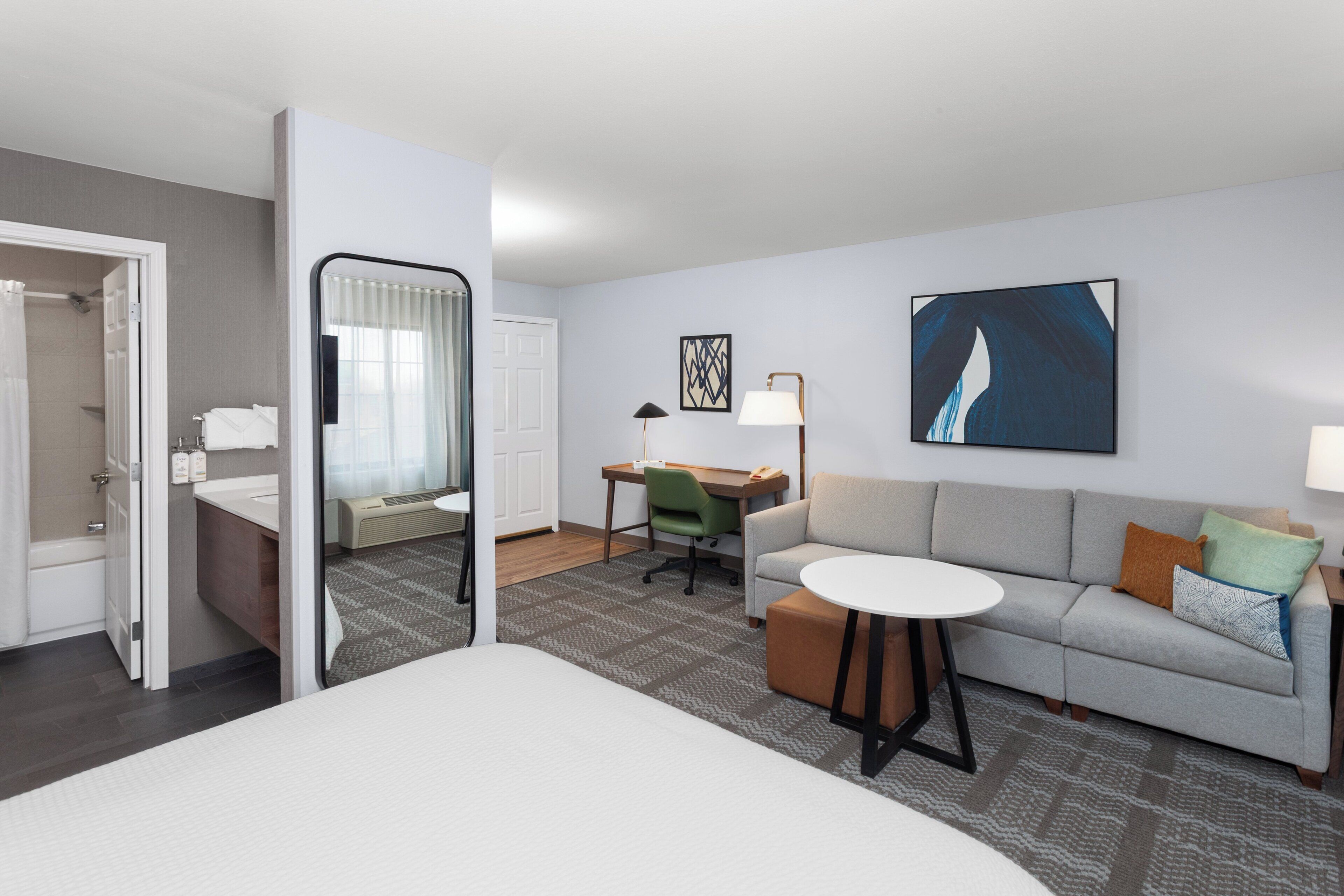 A hotel room with a bed, a desk, a sofa, a chair, and a bathroom.