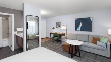 A hotel room with a bed, a desk, a sofa, a chair, and a bathroom.