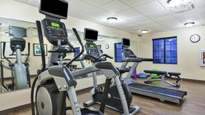 Un gimnasio con cintas de correr, elípticas y equipo de ejercicio.