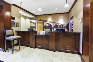 A reception desk with a chair, a computer, and a wall-mounted telephone. - Staybridge Suites Lansing - Okemos by IHG (Okemos)