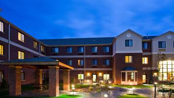 A multi-story building with a courtyard, outdoor seating, and illuminated windows.