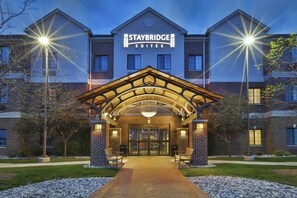 A Staybridge Suites hotel entrance with a brick facade, a covered entrance area, and a pathway leading to the main doors. - Staybridge Suites Lansing - Okemos by IHG (Okemos)