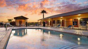 A swimming pool with lounge chairs and a lifeguard station at sunset. - Best Western Hebbronville Inn (Hebbronville)