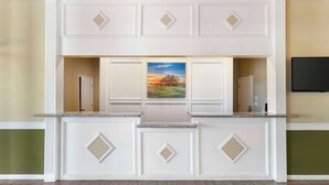 A kitchen with a central island, white cabinetry, and a painting above the island. - Best Western Hebbronville Inn (Hebbronville)