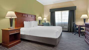 A hotel room with a large bed, two bedside tables with lamps, a desk, and a chair.