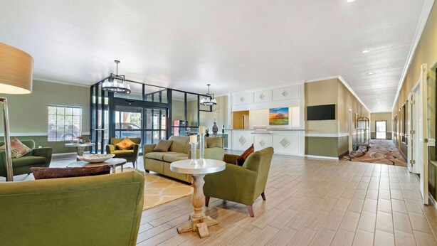 A spacious living area with a round table, green sofas, and a glass partition. - Best Western Hebbronville Inn (Hebbronville)