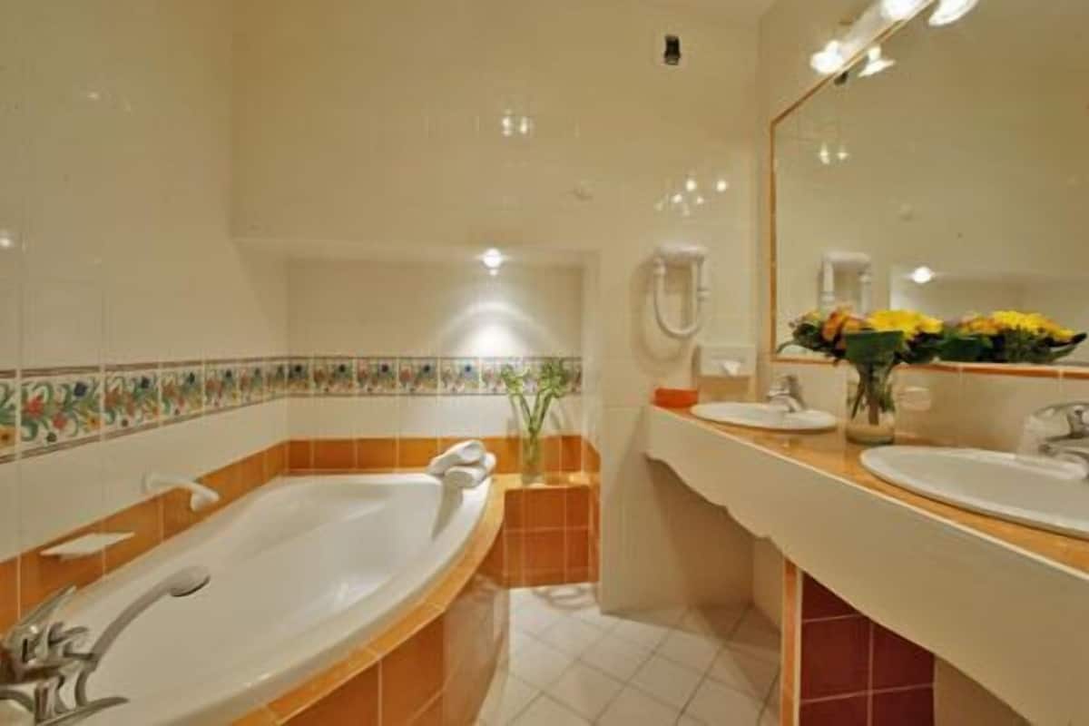 A bathroom with a bathtub, two sinks, and a mirror.