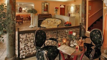 A dining area with a table set for two, two chairs, a decorative vase, and a mirror above the table.