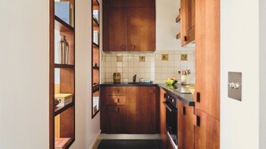 Une cuisine compacte avec des meubles en bois, un pare-feu en carreaux et un plan de travail noir.
