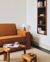 Een woonkamer met een bank, een salontafel, een bijzettafeltje, een lamp en een boekenkast.