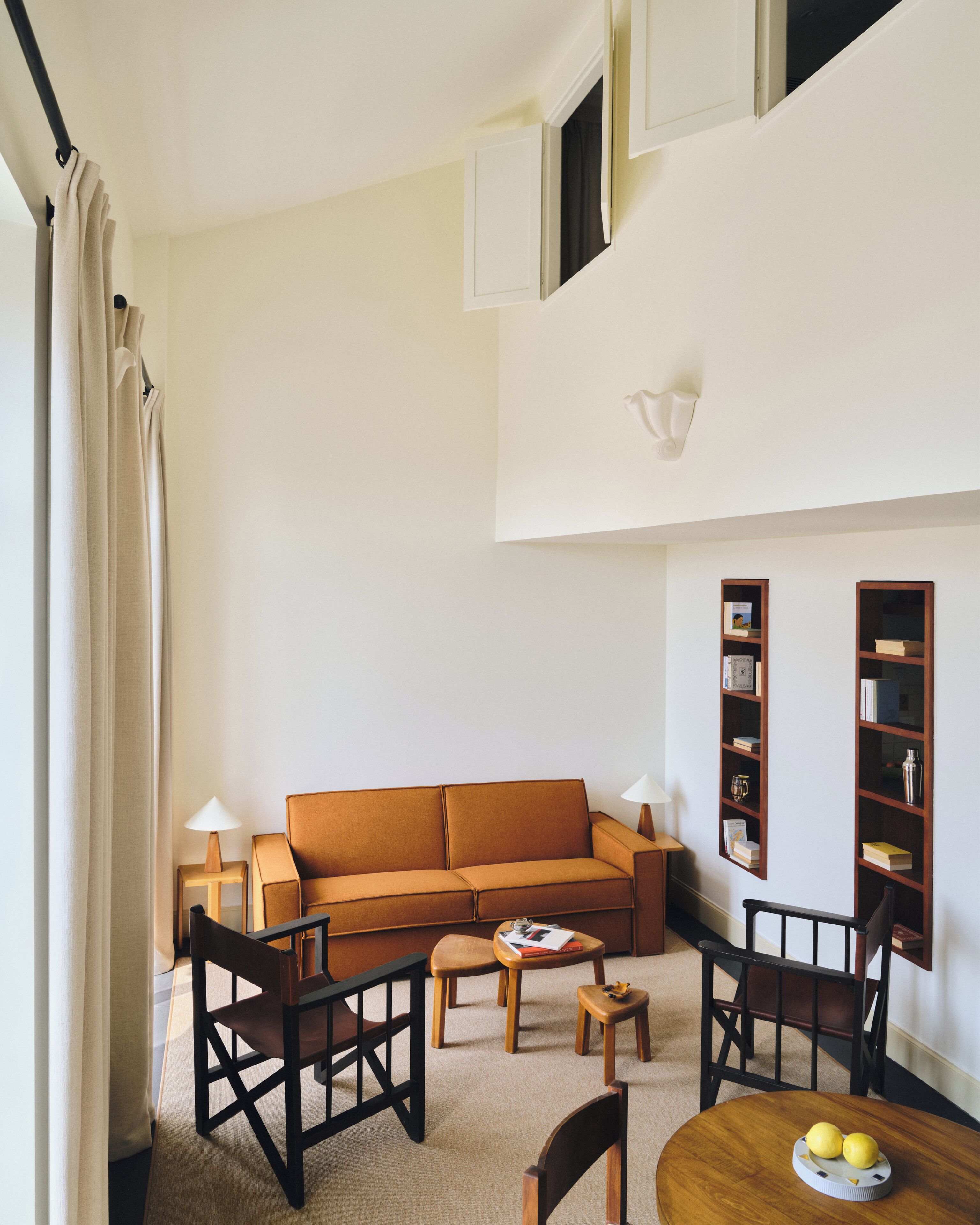 Un salon comprenant un canapé, des fauteuils, une table basse, une petite table avec des livres et une bibliothèque.