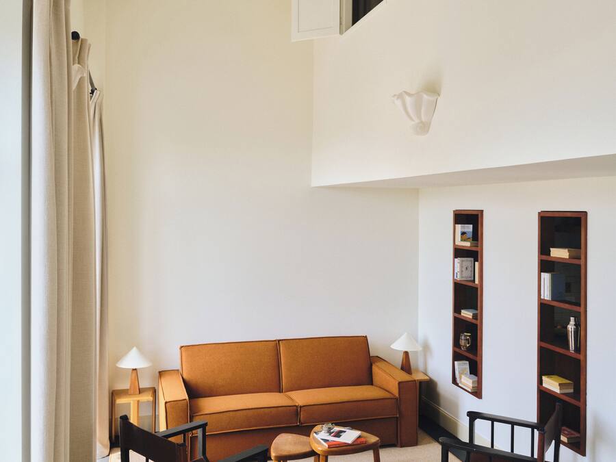 Un salon comprenant un canapé, des fauteuils, une table basse, une petite table avec des livres et une bibliothèque.