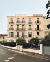 A multi-story building with balconies, a gated entrance, and a clear sky.