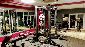 A gym with various exercise equipment, including a squat rack, bench press, and weight plates.