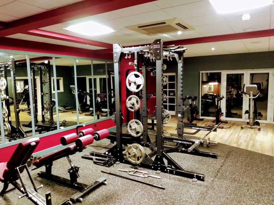 A gym with various exercise equipment, including a squat rack, bench press, and weight plates.