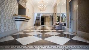 Un vaste hall d’entrée doté d’un sol à carreaux, d’un magnifique lustre et d’un escalier menant à l’étage supérieur.