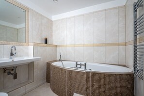 Bathroom features a bathtub, decorative border, and mosaic tile floor.