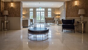 Un hall d’entrée spacieux avec une table ronde, deux fauteuils et un canapé.