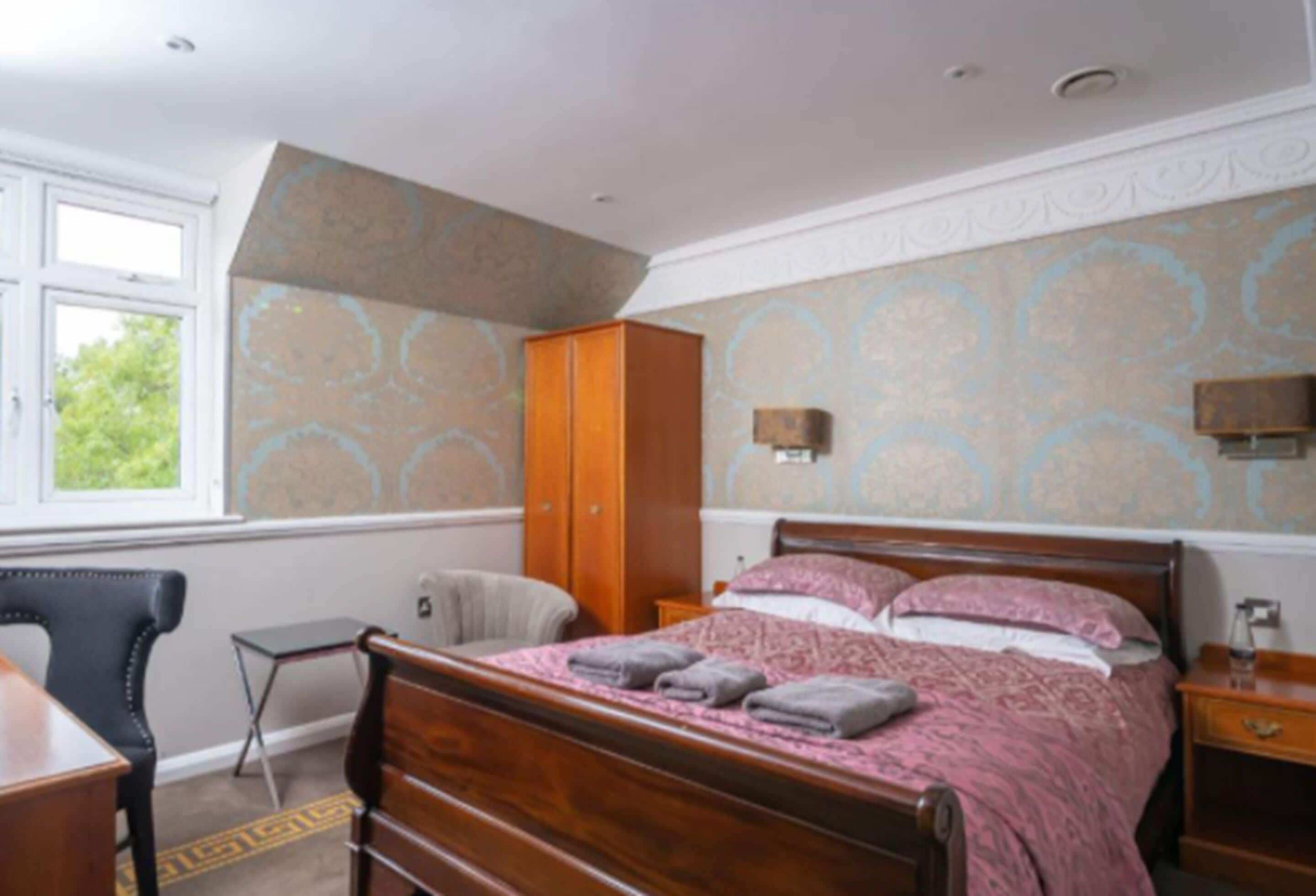 Un dormitorio con una cama de madera, un escritorio, una silla y un armario.