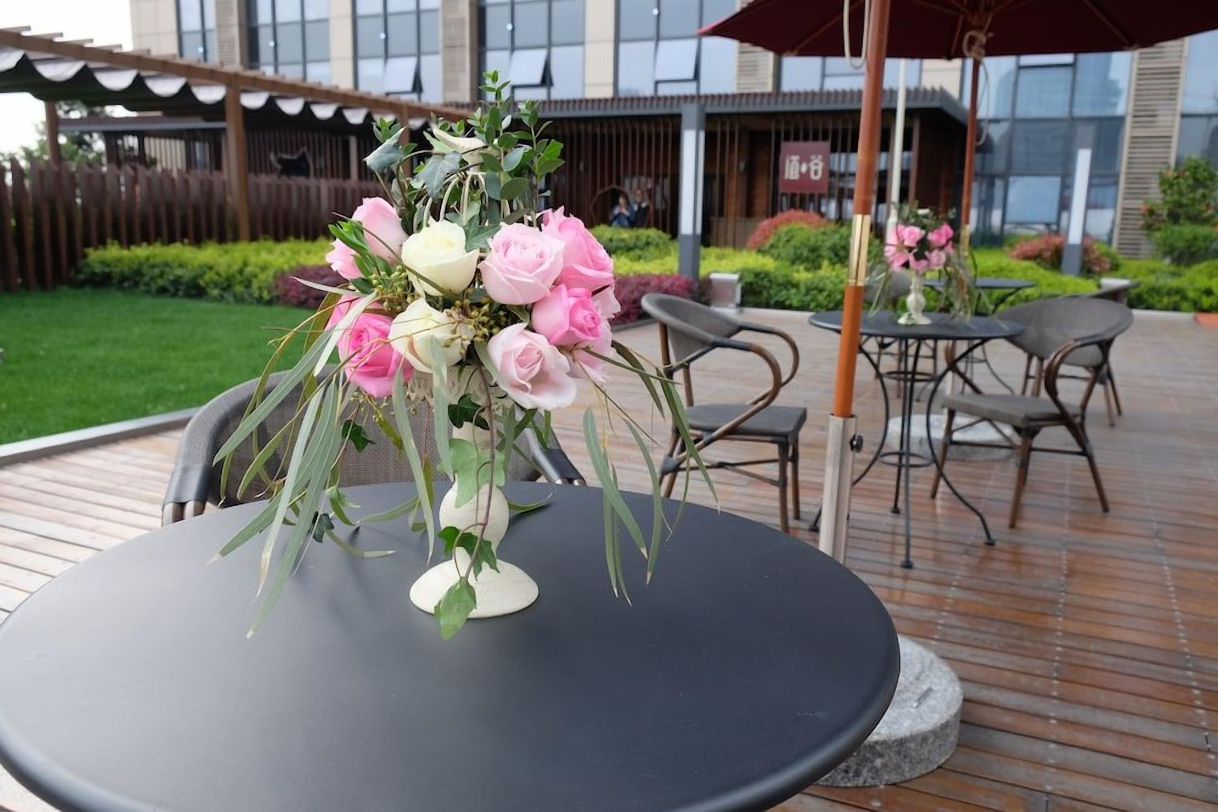 An outdoor seating area with a round table, chairs, and a decorative flower arrangement.