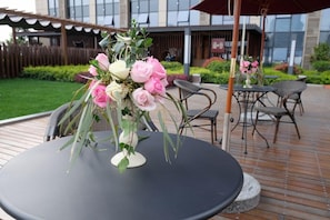 An outdoor seating area with a round table, chairs, and a decorative flower arrangement. - Blossom Hotel Hangzhou (Hangzhou)