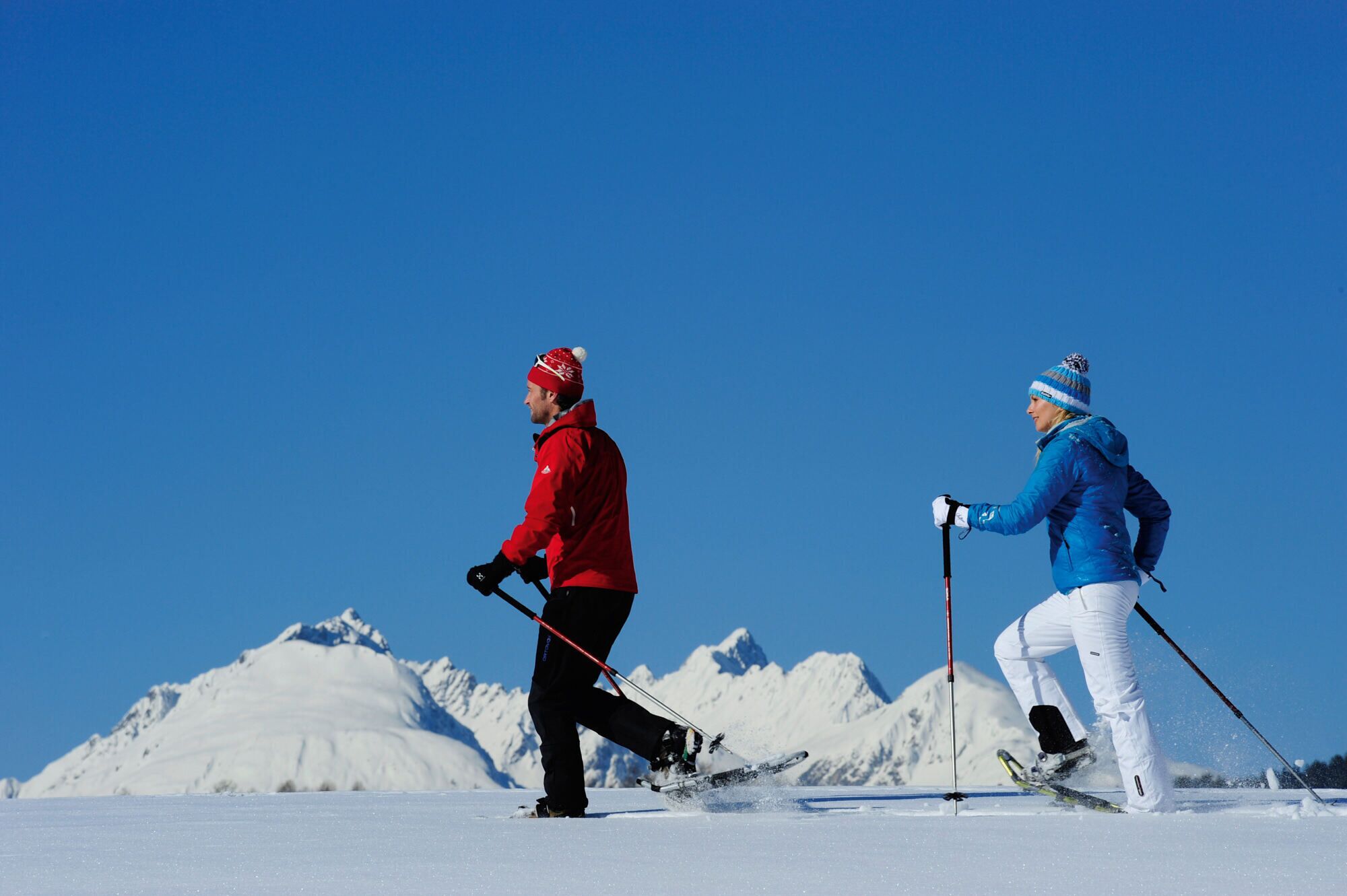 Two skiers on a snowy slope with a clear blue sky.