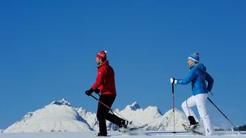 Two skiers on a snowy slope with a clear blue sky.