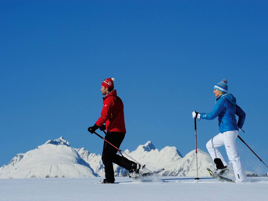 Two skiers on a snowy slope with a clear blue sky.