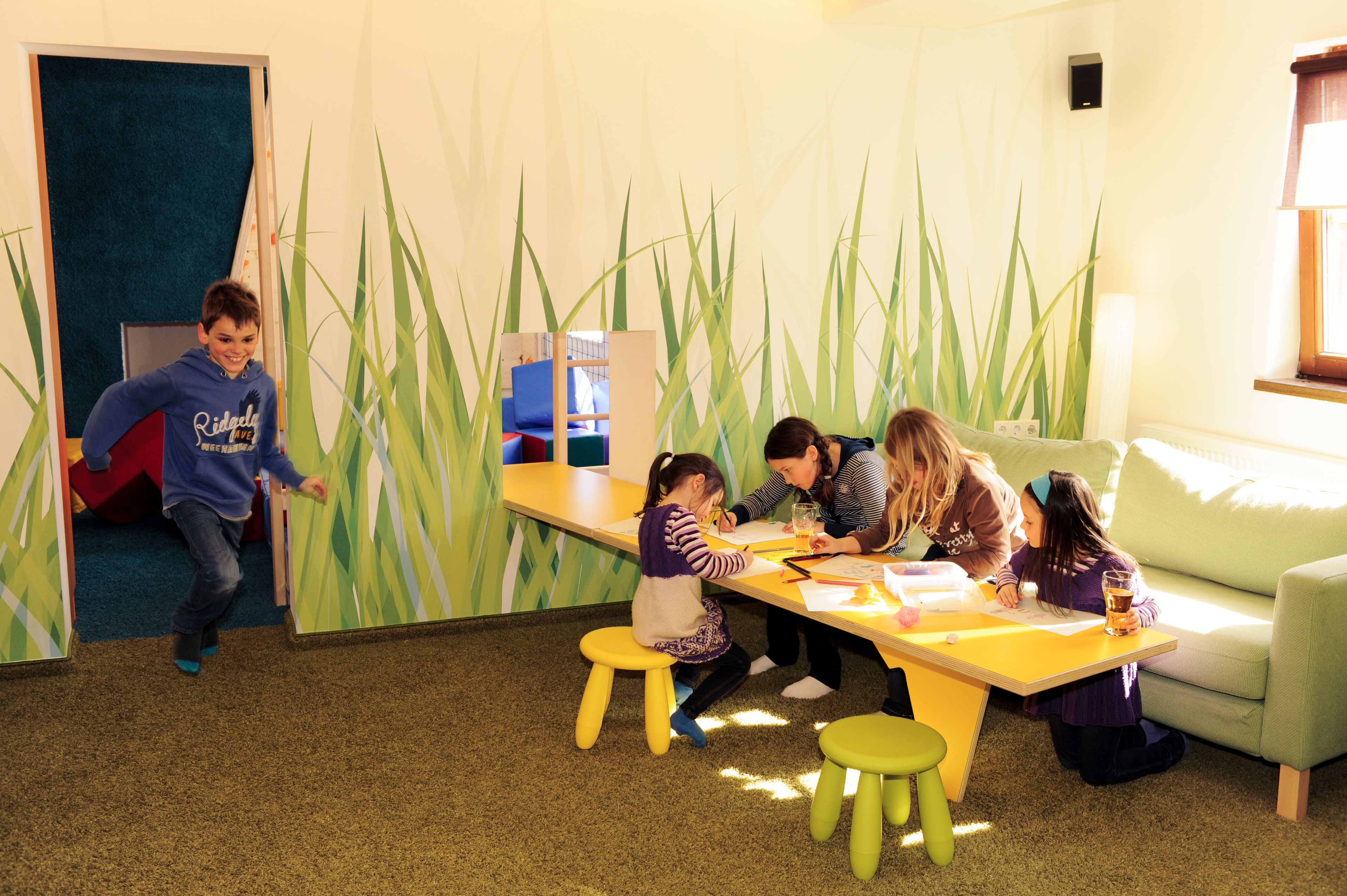 A group of children engaged in activities at a table with a play area in the background.