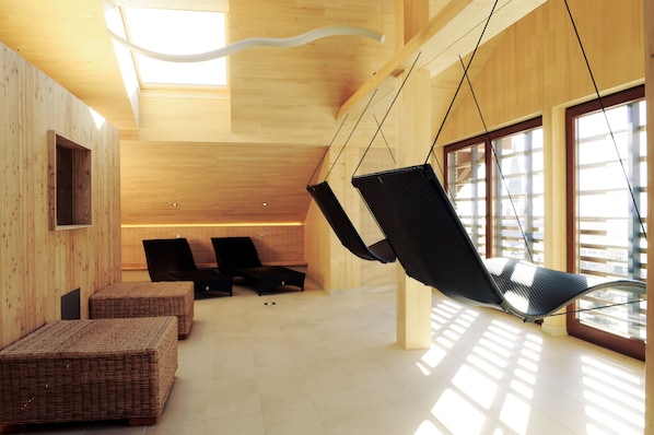 A modern interior with hanging chairs, wooden walls, and large windows.