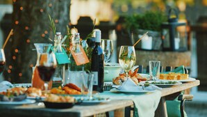 A dining table set with plates of food, glasses, and bottles, likely in an outdoor or semi-outdoor setting with natural light and blurred background. - Der Stern - Wirtshaus und Landhotel für Generationen seit 1509 (Obsteig)