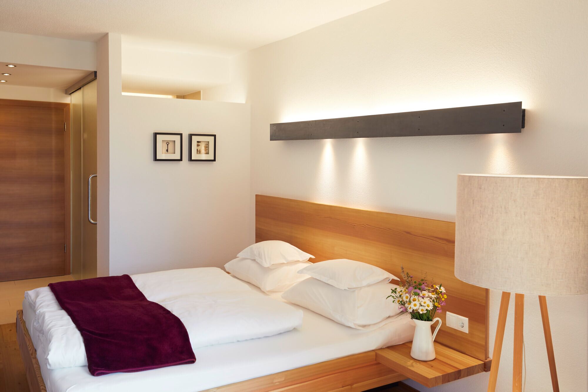 A hotel room with a bed, a nightstand with a lamp, a wooden headboard, and a wardrobe.